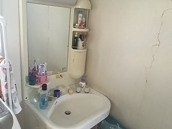 施工前の洗面化粧台です。<br>壁にはヒビが入っていました。<br>洗面化粧台は収納スペースが少なく、いろいろなところに物が置いてありますね。