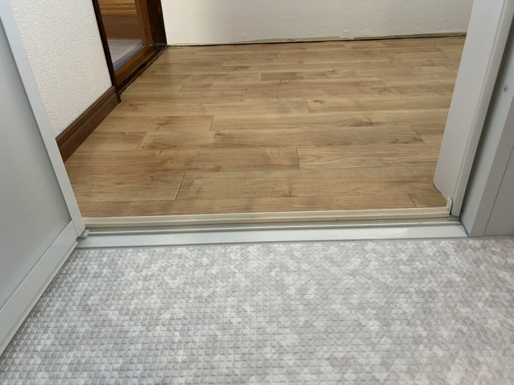 出入口の段差は完全に解消されました。洗面室との床がフラットになり、つまずく心配なく安全に出入りできます。床にはTOTOサザナの「ほっカラリ床」を採用し、冬場の一歩目もヒヤッとしません。
