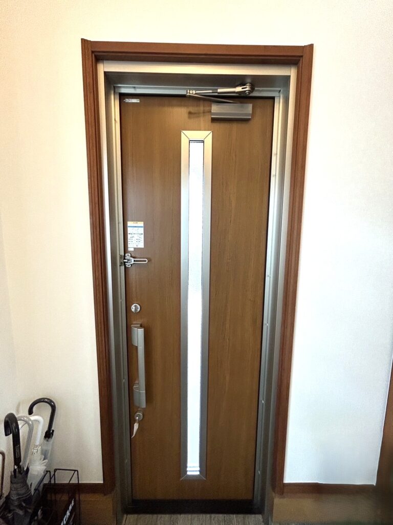 こちらは室内側から見た玄関ドアです。YKK APのドアリモは断熱性能にも優れており、冬の冷気や夏の熱気の侵入を抑え、室内の快適性を高めます。中央のスリットガラスから光が差し込み、以前より玄関全体が明るくなりました。