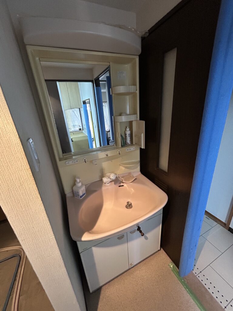 こちらが施工前の洗面化粧台です。収納スペースが少なく物が表に出てしまいがちで、洗面ボウルも小さいため、水はねなど使い勝手の面でもお悩みでした。